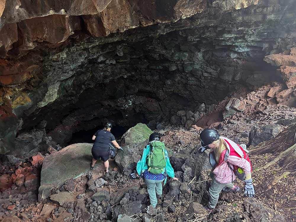 Students hiking into lava tube cave during geology field study