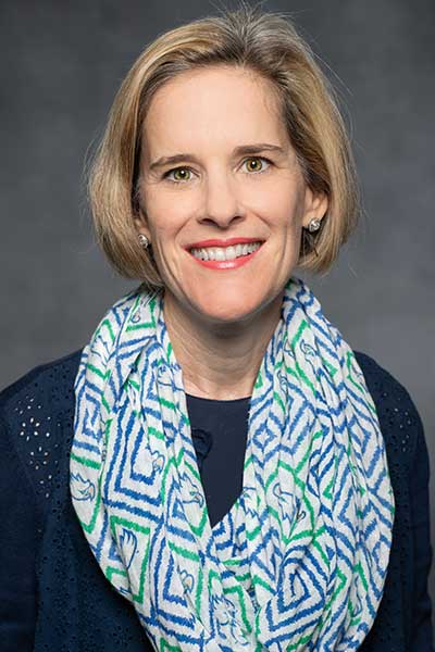 Woman in dark top wearing blue and green scarf