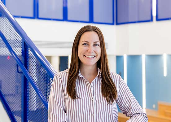 FGCU hospitality alum stands inside campus academic building.