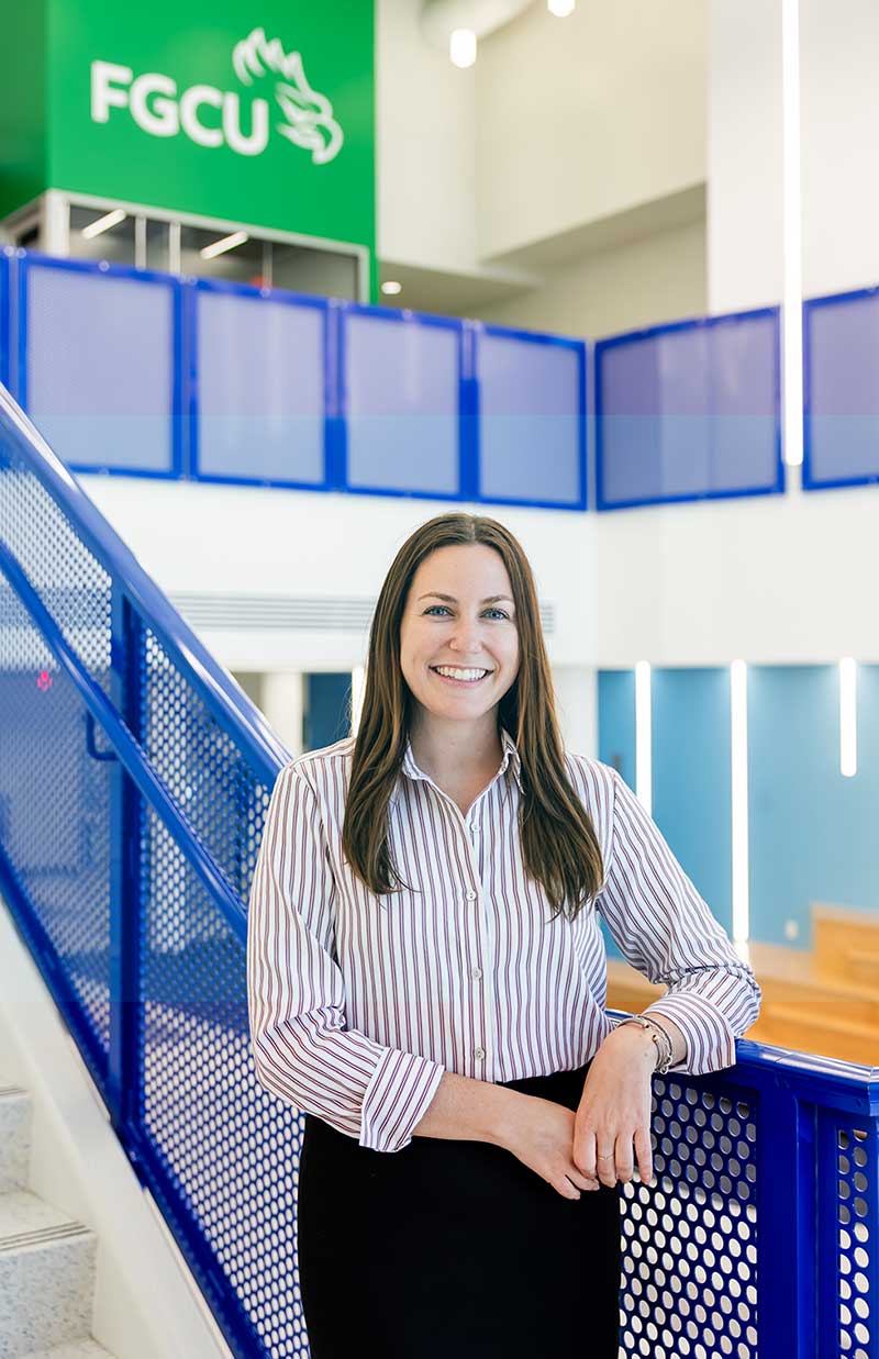 FGCU hospitality alum stands inside campus academic building.