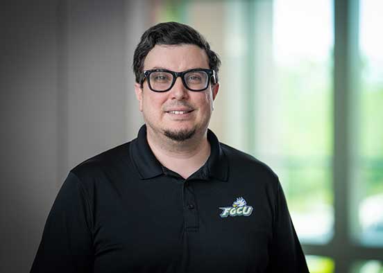 Person in black shirt with FGCU logo poses indoors