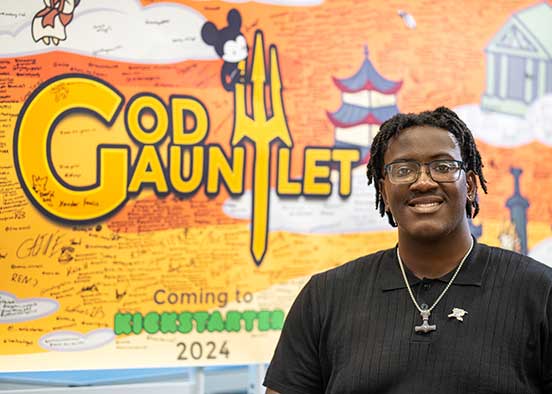 FGCU student entrepreneur with God Gauntlet display promoting startup success.