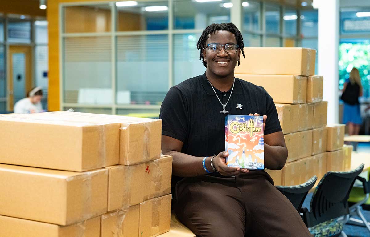 FGCU student entrepreneur with God Gauntlet display promoting startup success.