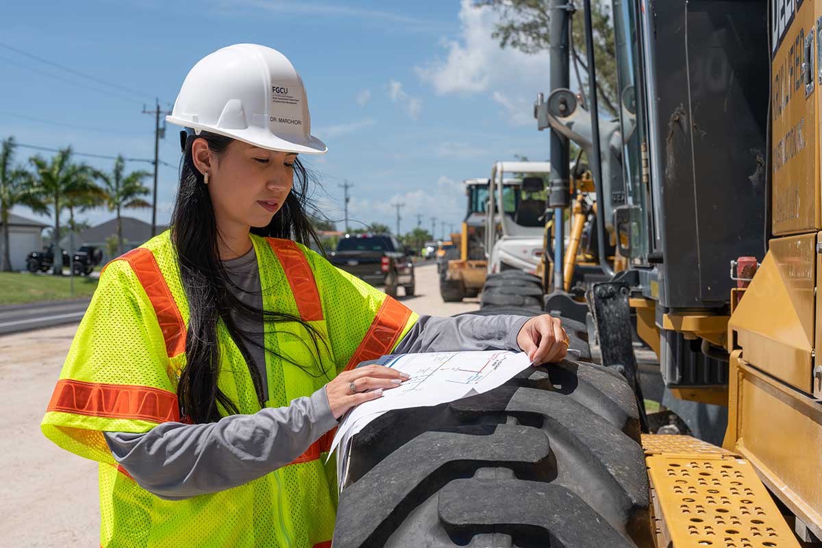 Engineer reviews construction plans beside roadwork equipment