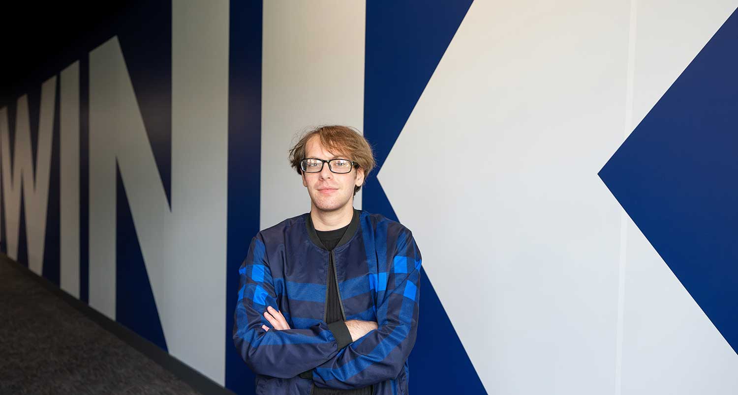 Student standing front of WINK logo in production and broadcasting facility