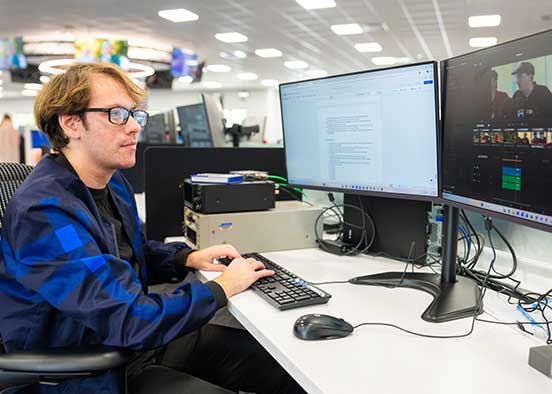 Student edits digital media content on dual monitors in production lab