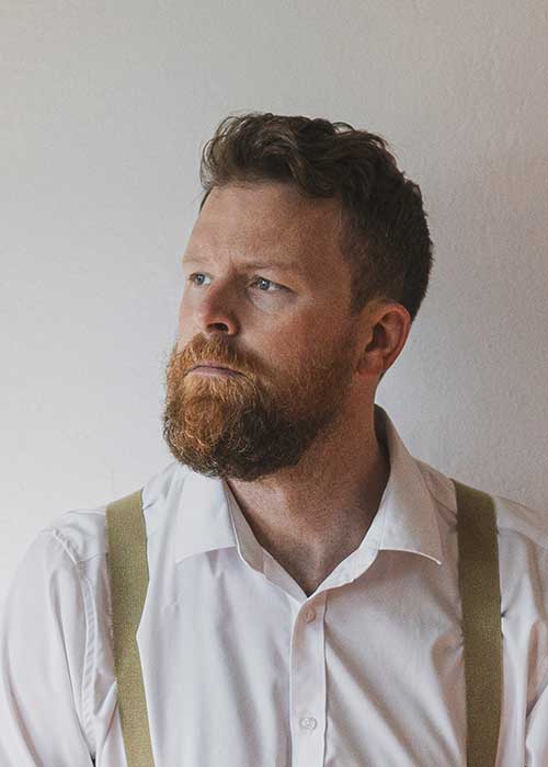 Bearded man in white shirt looking toward window light