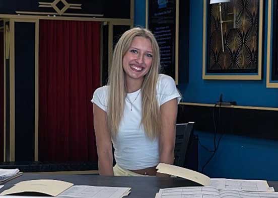 FGCU student standing at registration desk in a theater